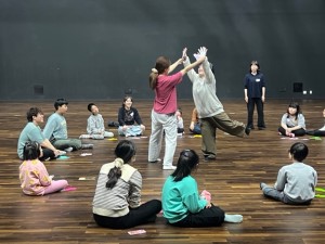 원 모양으로 여럿이서 앉고, 두 명이 그 원 안에 들어가서 두 팔을 뻗어 두 손뼉치는 사진